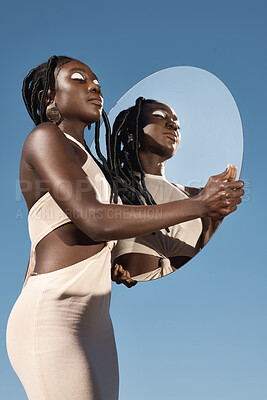 Buy stock photo Shot of an attractive young woman holding a mirror with her reflection in it against a sky background