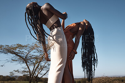 Buy stock photo Shot of two attractive young women holding hands against an African nature background