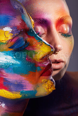 Buy stock photo Studio shot of two young women posing with multi-coloured paint on her face