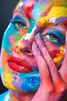 Buy stock photo Studio shot of a young woman posing with multi-coloured paint on her face