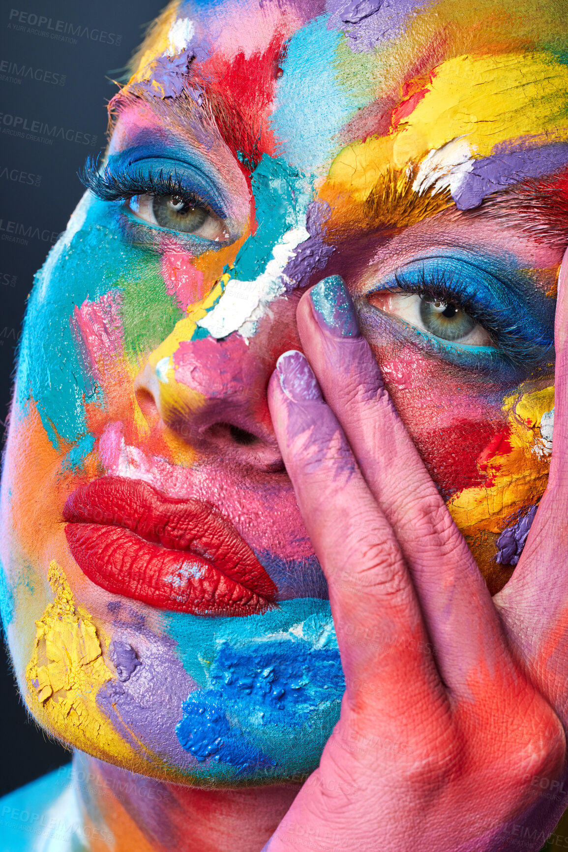 Buy stock photo Studio shot of a young woman posing with multi-coloured paint on her face