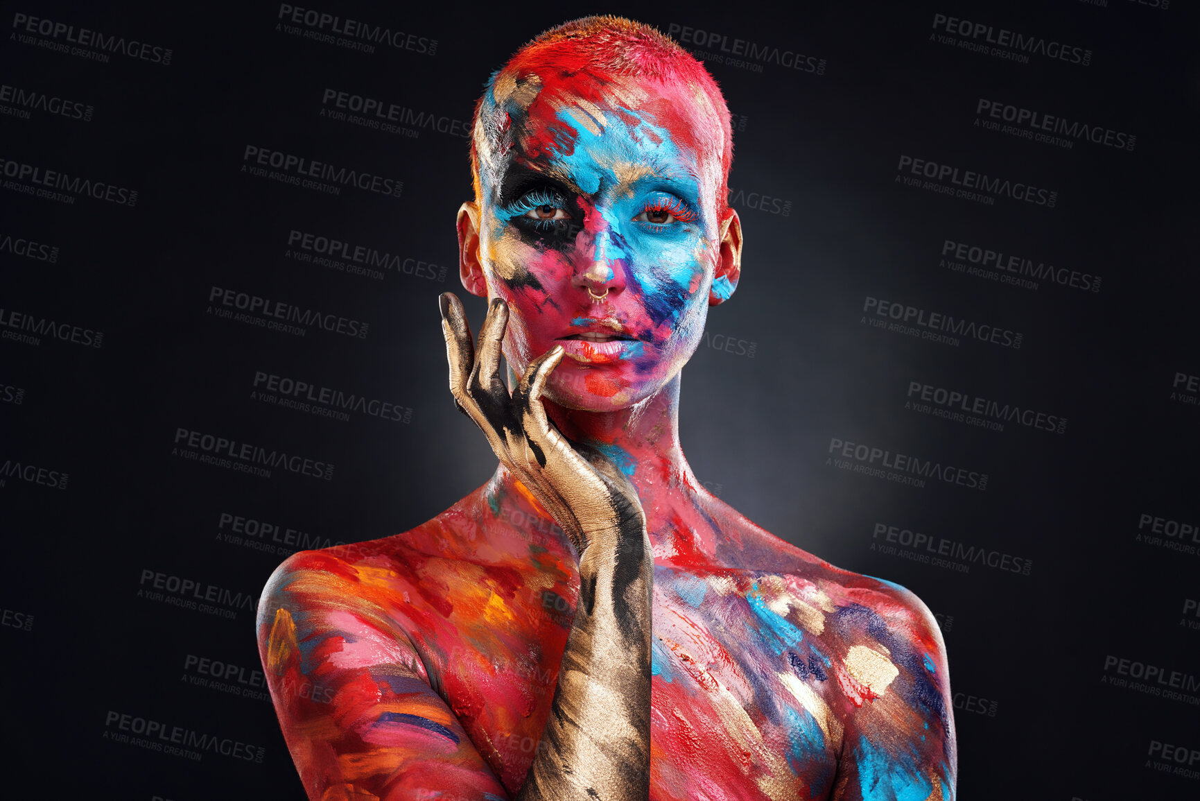 Buy stock photo Shot of an attractive young woman posing alone in the studio with paint on her face and body