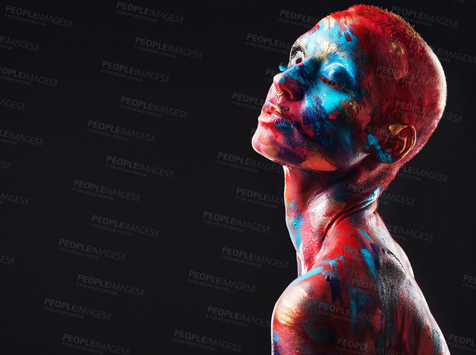 Buy stock photo Shot of an attractive young woman posing alone in the studio with paint on her face and body