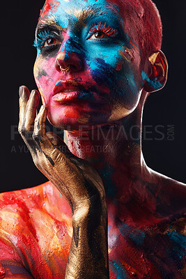 Buy stock photo Shot of an attractive young woman posing alone in the studio with paint on her face and body