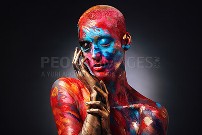 Buy stock photo Shot of an attractive young woman posing alone in the studio with paint on her face and body