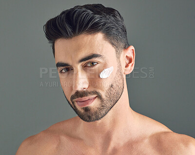 Buy stock photo Studio shot of a handsome young man posing with moisturiser on his face