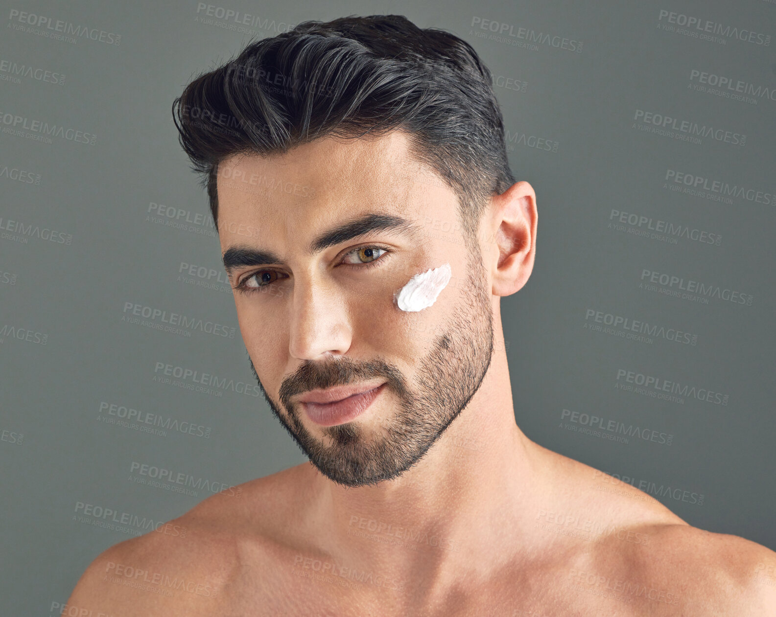 Buy stock photo Studio shot of a handsome young man posing with moisturiser on his face