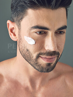 Buy stock photo Studio shot of a handsome young man posing with moisturiser on his face