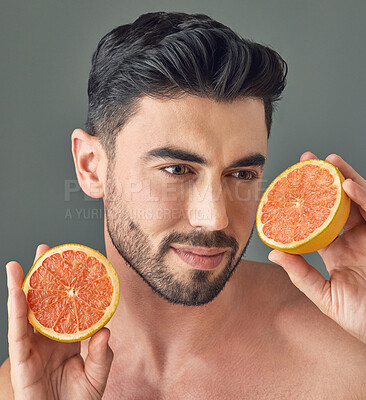 Buy stock photo Studio shot of a handsome young man holding up a grapefruit