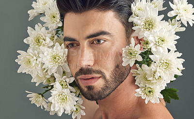 Buy stock photo Studio shot of a handsome young man posing with flowers against a grey background