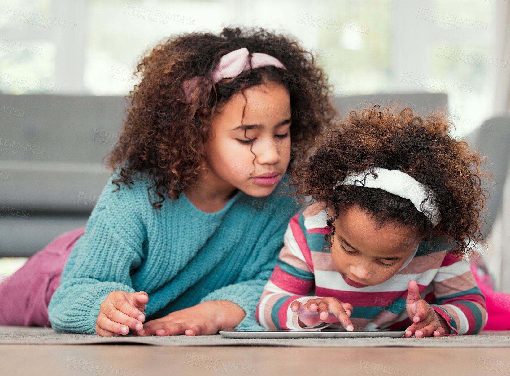 Buy stock photo Shot of two little girls playing on a digital tablet together at home