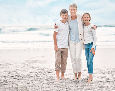 Buy stock photo Shot of a mature woman and her grandchildren bonding at the beach