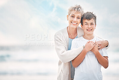 Buy stock photo Shot of a mature woman and her grandson bonding at the beach
