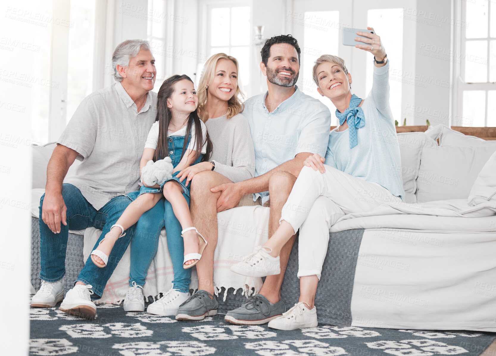 Buy stock photo Happy family, selfie and girl relax with parents, grandparents and smartphone on sofa in a living room, happy and bonding. Family, phone and multi generations smile for picture while sitting on couch