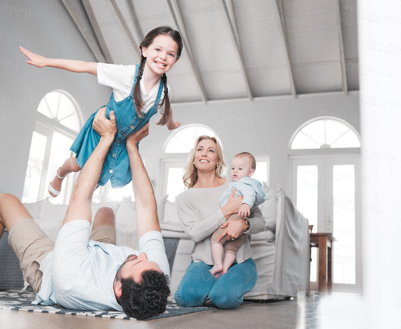 Buy stock photo Father, play game and girl in the living room with baby and mom on the floor in house. Trust, love and support as happy child having fun or fly, care and joy with her family in home lounge together