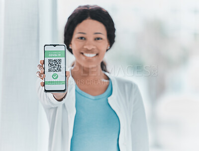 Buy stock photo Shot of a young woman standing alone in the clinic and showing her Covid passport on her cellphone