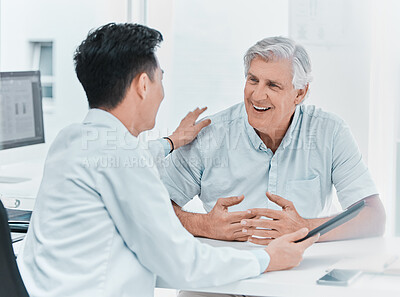 Buy stock photo Shot of a mature man sitting with his doctor and going over his medical results on a digital tablet in the clinic