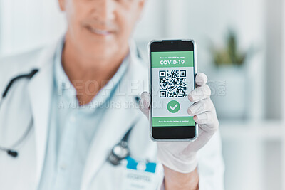 Buy stock photo Shot of a male doctor holding a smartphone depicting a QR code to be scanned