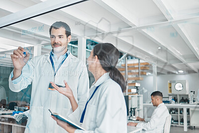 Buy stock photo Shot of two young scientists brainstorming with notes on a glass screen in a lab