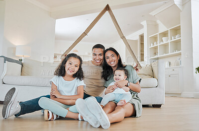 Buy stock photo Shot of a beautiful family sitting on the lounge floor while holding a cardboard house over their heads