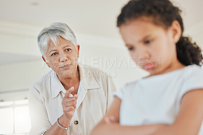Buy stock photo Shot of a mature woman looking annoyed with her granddaughter at home