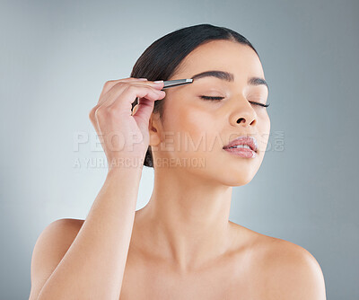 Buy stock photo Woman, eyebrow and tweezer on face for beauty, skincare or hair removal with product isolated on grey studio background. Cosmetics, facial plucking and model grooming for health, wellness and glow