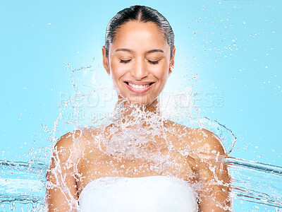 Buy stock photo Water, splash and shower with woman in studio for hygiene, beauty and skincare. Wellness, cleaning and fresh with face of female model on blue background for spa, cosmetics and liquid mockup space