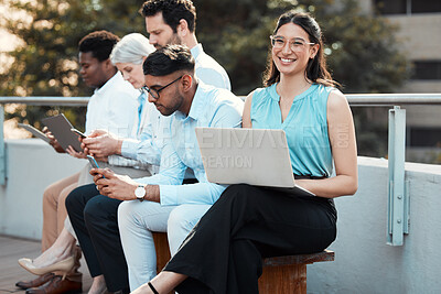 Buy stock photo Shot of an attractive young businesswoman sitting outside with her colleagues and using her laptop