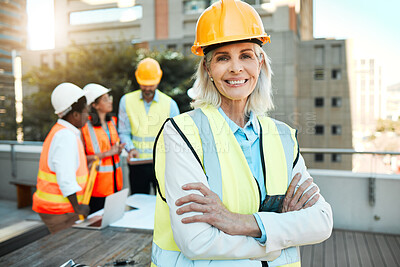 Buy stock photo Shot of a mature contractor standing outside with her arms folded while her colleagues work behind her