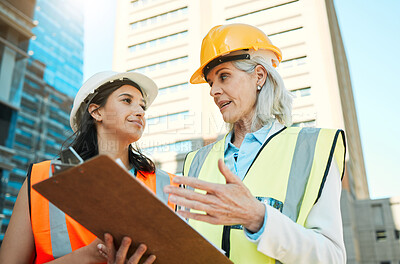 Buy stock photo Low angle shot of two contractors standing outside together and having a discussion over a clipboard
