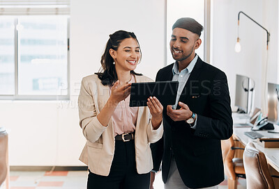 Buy stock photo Shot of two young businesspeople standing in the office together and using a digital tablet