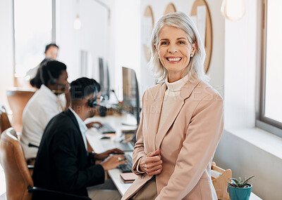 Buy stock photo Shot of a mature businesswoman sitting in the office while her team work behind her