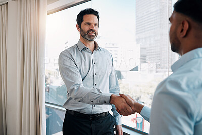 Buy stock photo Shot of a mature businessman standing and shaking a colleague's hand in the office