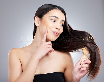 Buy stock photo Studio shot of an attractive young woman brushing her hair against a grey background