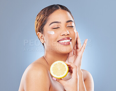 Buy stock photo Shot of a young woman holding half a lemon against a grey background