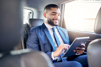 Buy stock photo Shot of a young businessman using a digital tablet while travelling in a car