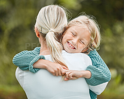 Buy stock photo Shot of a little girl and her mother sharing a hug while outside
