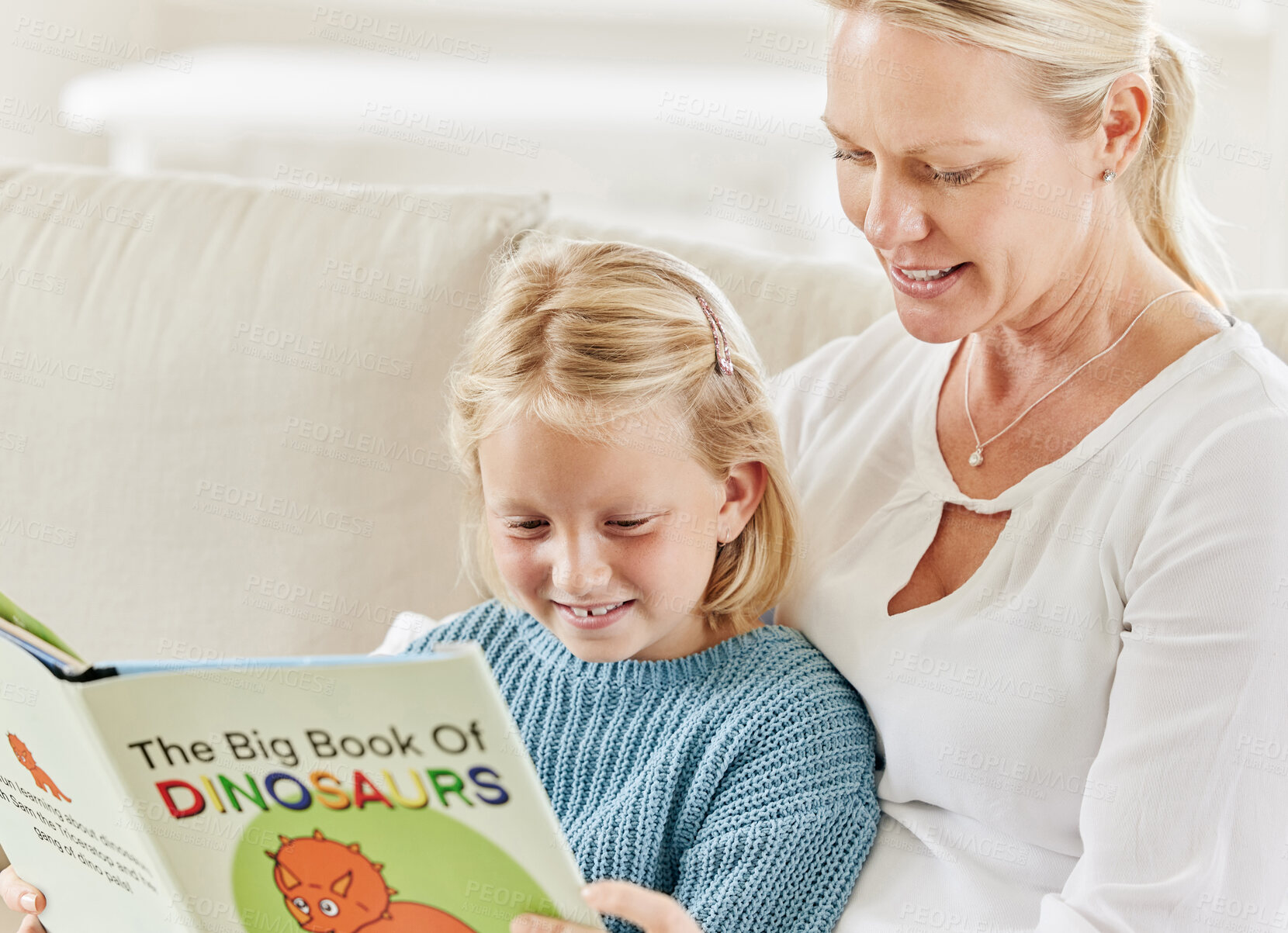 Buy stock photo Shot of a young mother and daughter reading on the sofa at home