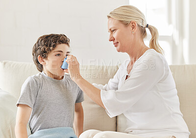 Buy stock photo Shot of a mother helping her son use his inhaler on the sofa at home