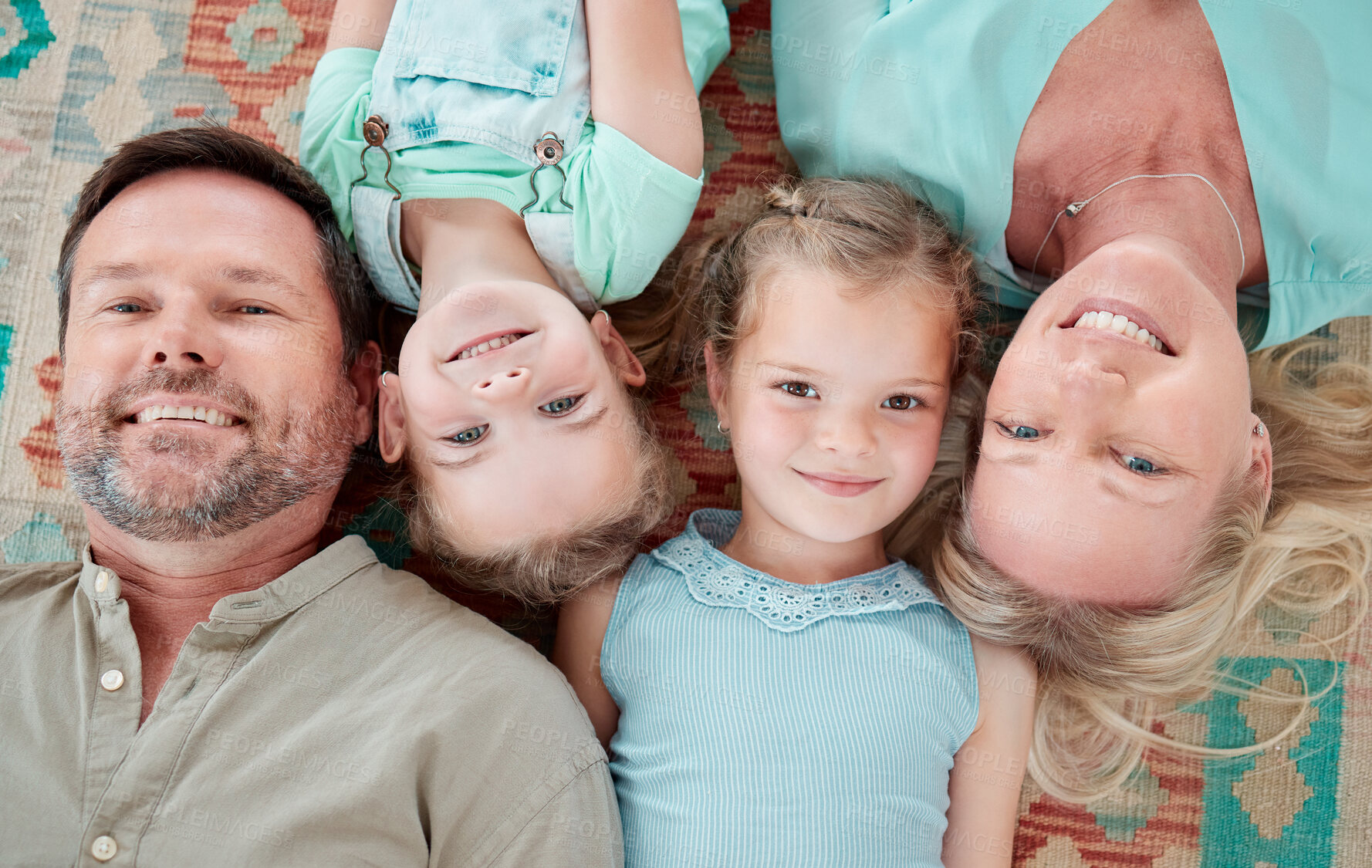 Buy stock photo Shot of a couple and their two daughters lying in a row