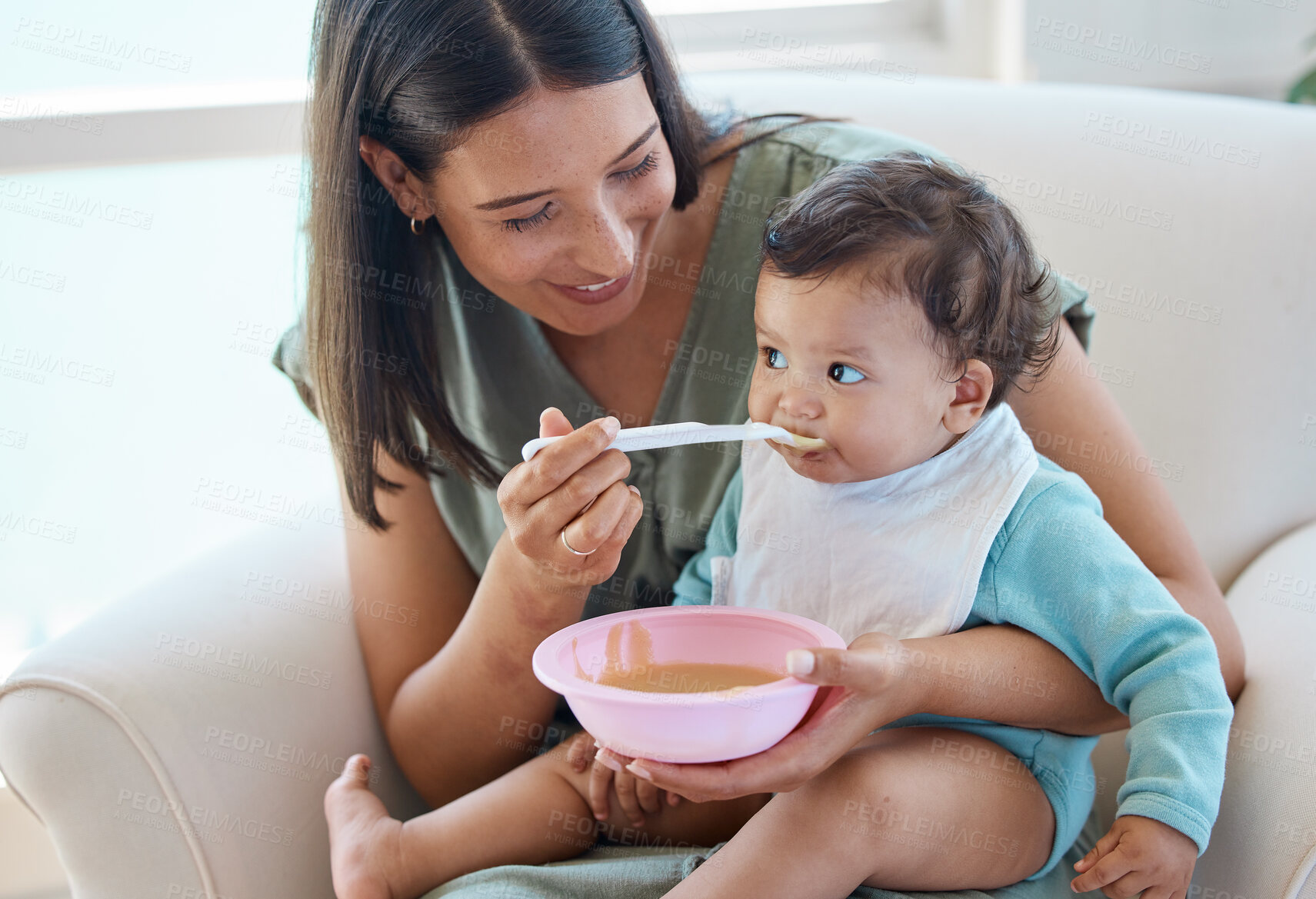 Buy stock photo Shot of a mother feeding her baby while sitting on a chair
