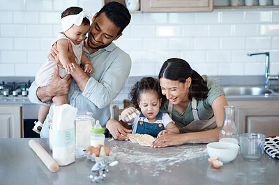 Buy stock photo Shot of a woman baking in the kitchen with her husband and two daughters