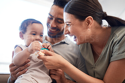 Buy stock photo Shot of a young couple bonding with their baby girl on a sofa at home