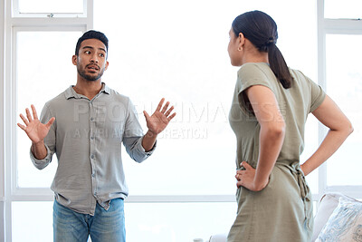 Buy stock photo Shot of a young couple looking frustrated and arguing at home