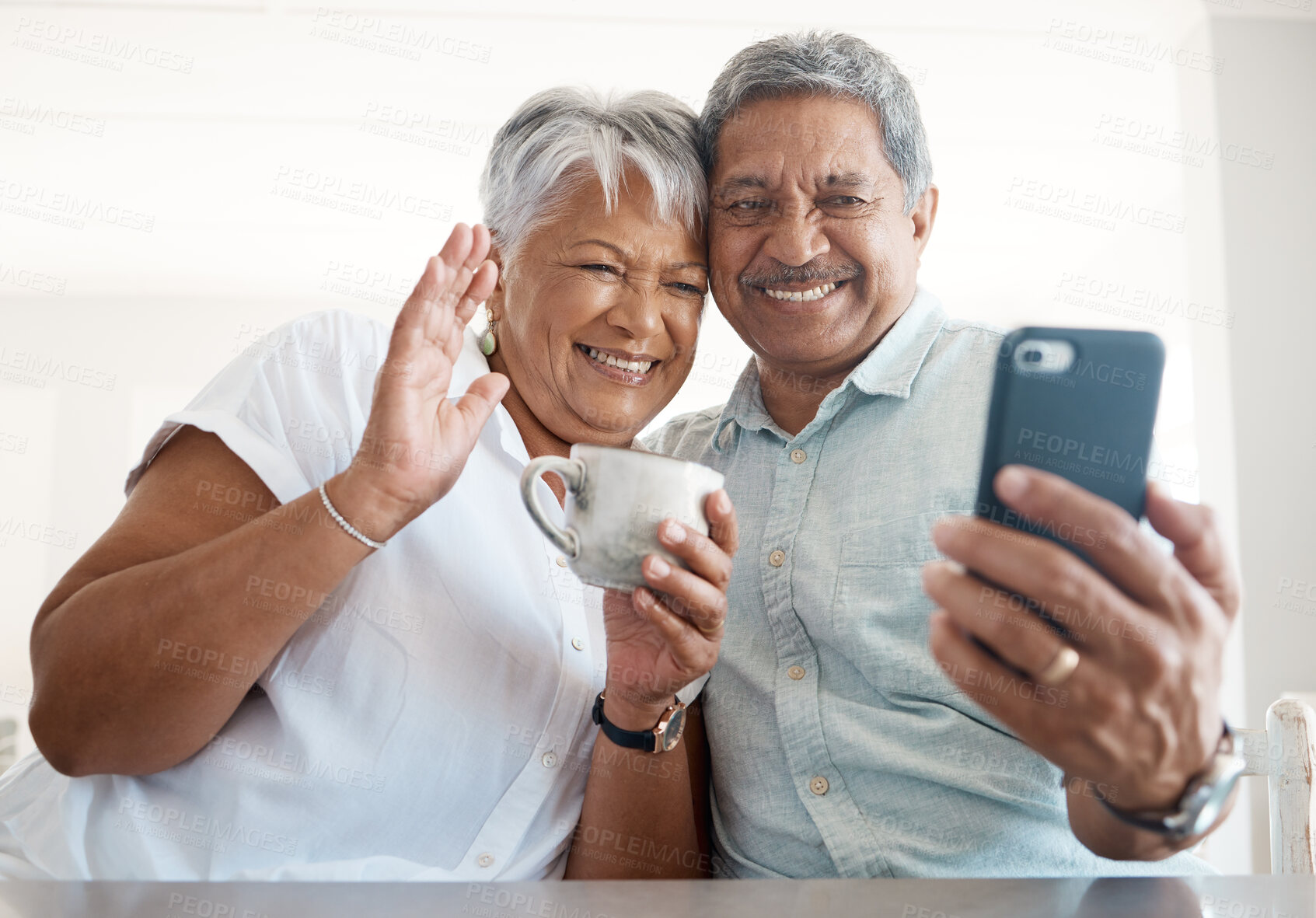 Buy stock photo Senior couple, video call and phone in home with wave, smile and coffee to start morning in retirement. People, woman and man with hello for contact, chat and mobile app with tea cup at apartment