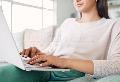 Buy stock photo Shot of a beautiful young woman using her laptop while sitting on the couch at home