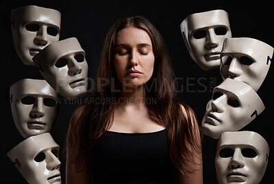 Buy stock photo Studio shot of a woman standing with her eyes closed while surrounded by masks
