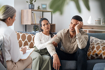 Buy stock photo Shot of a young couple sitting together and looking concerned during a consultation with a psychologist