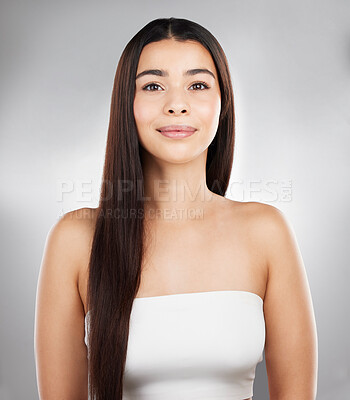 Buy stock photo Studio portrait of a beautiful young woman showing off her long silky hair against a grey background