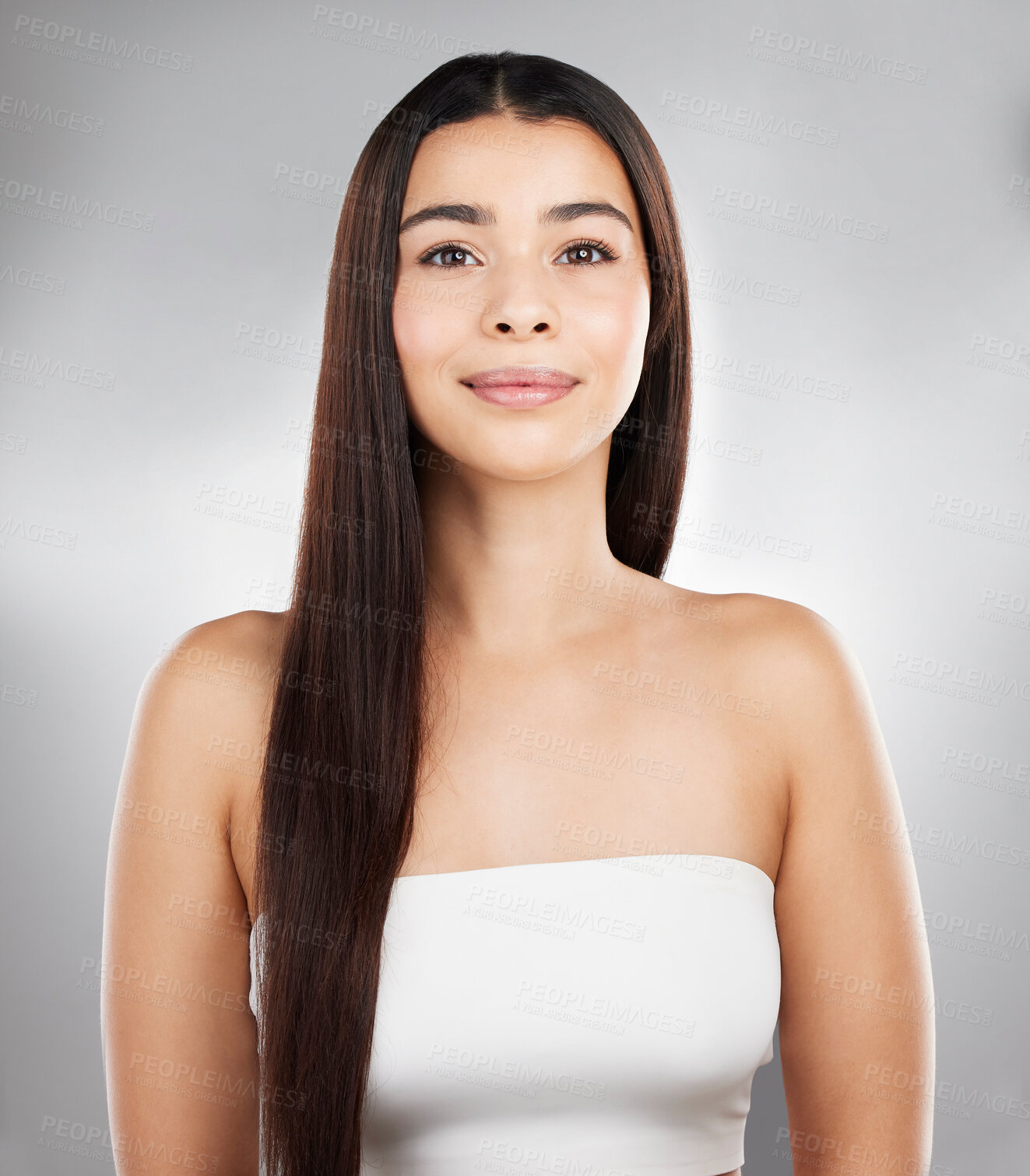 Buy stock photo Studio portrait of a beautiful young woman showing off her long silky hair against a grey background